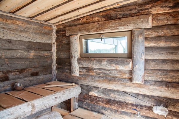 Sauna, jonka seinät on tehty kelopaneelista ja lauteet kelolankuista.